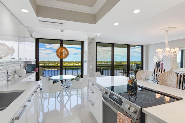 kitchen with stainless steel range with electric stovetop, white cabinetry, and hanging light fixtures