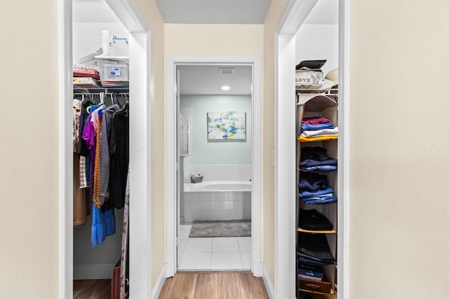 walk in closet with light hardwood / wood-style floors