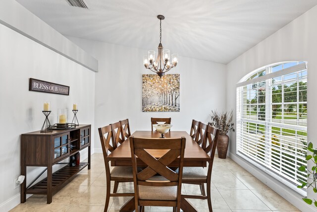 dining room featuring a notable chandelier, light tile patterned flooring, and vaulted ceiling