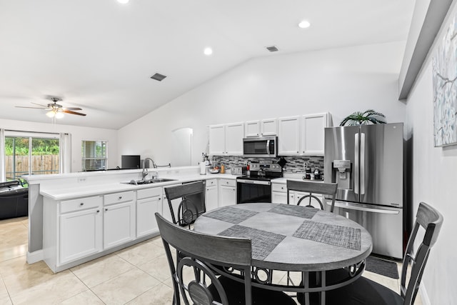 kitchen featuring sink, kitchen peninsula, appliances with stainless steel finishes, lofted ceiling, and white cabinets