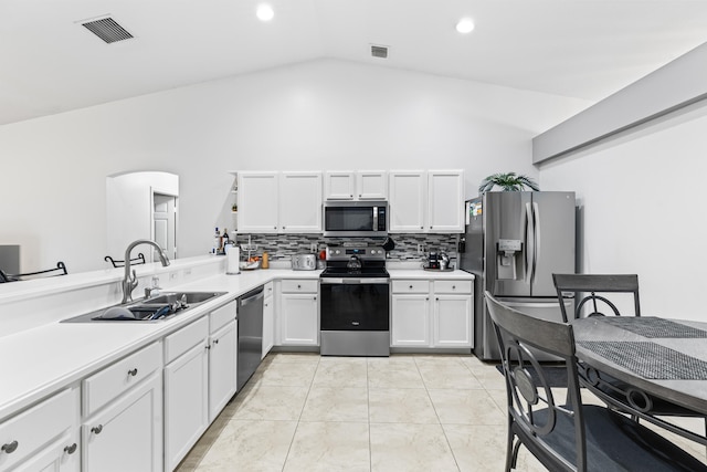 kitchen featuring stainless steel appliances, white cabinetry, sink, tasteful backsplash, and lofted ceiling