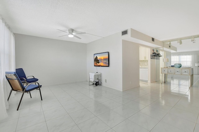 unfurnished room featuring a textured ceiling, track lighting, ceiling fan, and light tile patterned flooring