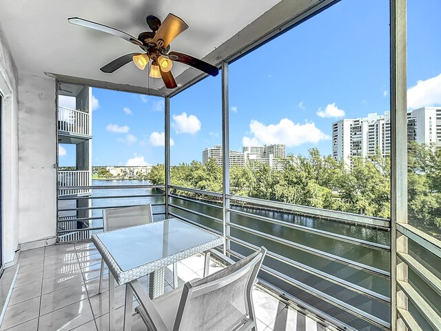 unfurnished sunroom with a wealth of natural light, a water view, and ceiling fan