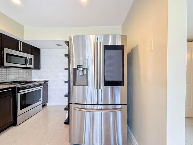 kitchen featuring sink, light tile patterned floors, appliances with stainless steel finishes, tasteful backsplash, and light stone counters