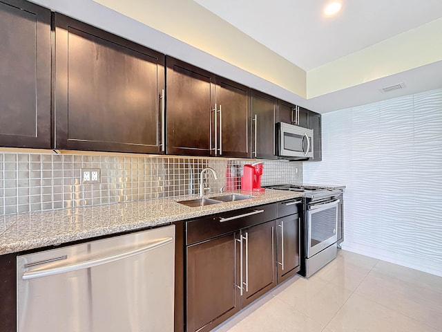 kitchen featuring stainless steel dishwasher, light tile patterned floors, backsplash, and stone counters