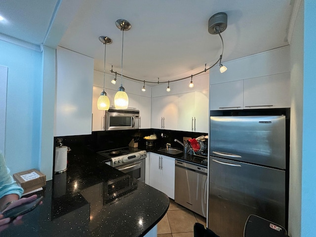 kitchen with stainless steel appliances, sink, pendant lighting, white cabinetry, and light tile patterned flooring