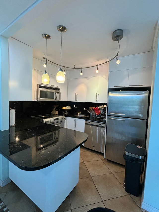 kitchen with kitchen peninsula, backsplash, stainless steel appliances, white cabinets, and hanging light fixtures