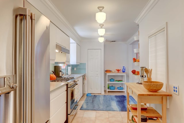 kitchen with crown molding, stainless steel appliances, light tile patterned floors, decorative backsplash, and white cabinets