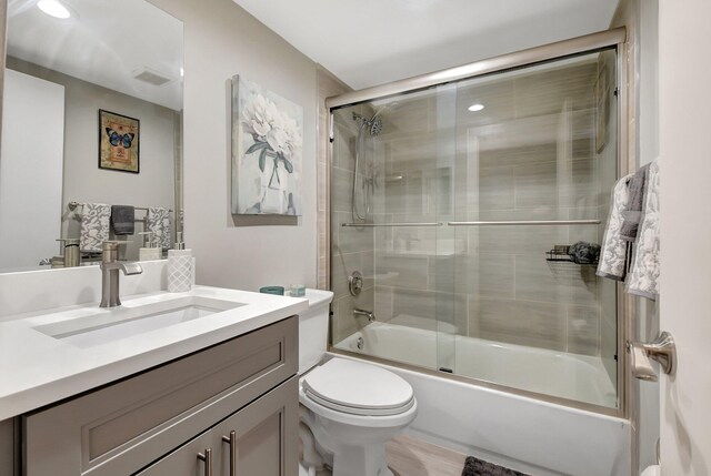 full bathroom featuring vanity, hardwood / wood-style flooring, toilet, and enclosed tub / shower combo