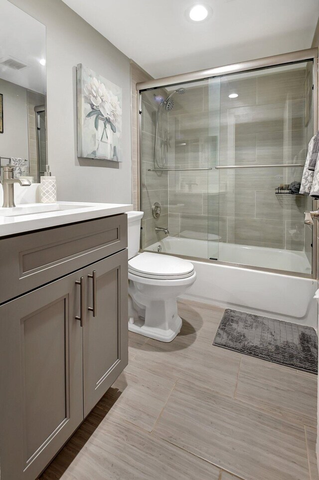 full bathroom with shower / bath combination with glass door, vanity, and toilet