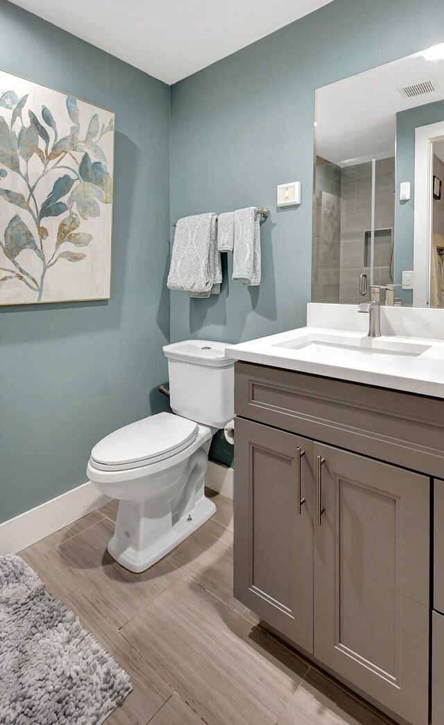 bathroom featuring vanity, hardwood / wood-style flooring, toilet, and a shower with door