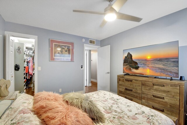 bedroom with ceiling fan, a walk in closet, and a closet