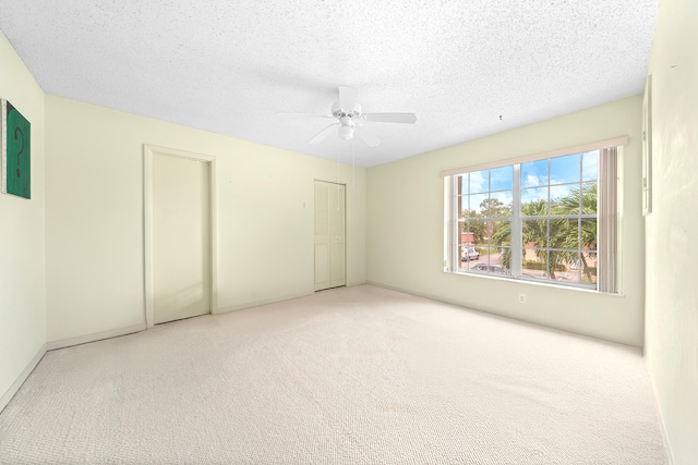 unfurnished bedroom featuring ceiling fan, a textured ceiling, and light carpet