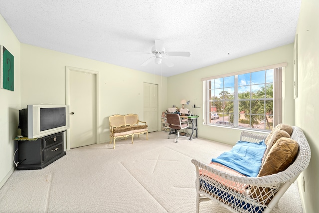 sitting room with ceiling fan, a textured ceiling, and carpet flooring