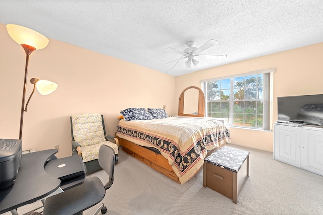 carpeted bedroom featuring ceiling fan and a textured ceiling