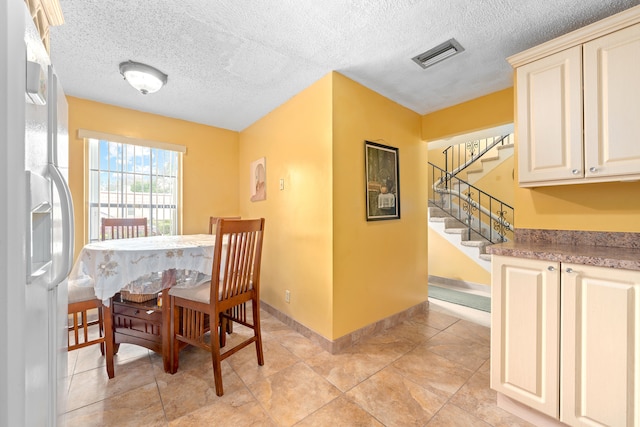 dining space with a textured ceiling and light tile patterned floors