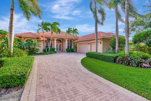 mediterranean / spanish-style home featuring a garage, french doors, and a front yard