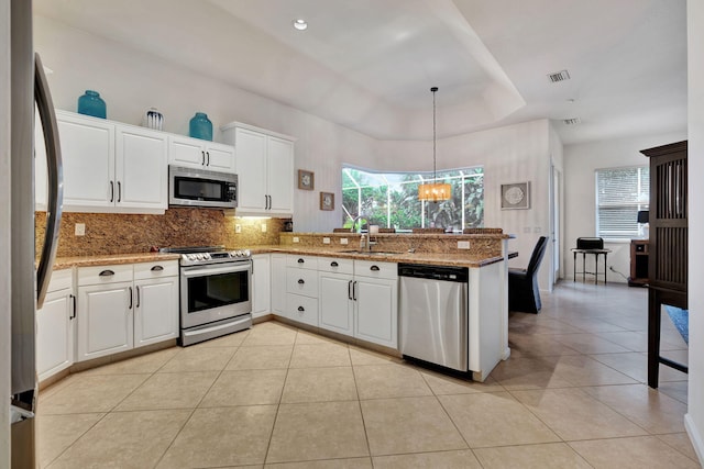 kitchen featuring appliances with stainless steel finishes, decorative light fixtures, sink, white cabinets, and kitchen peninsula