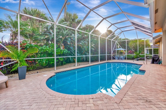 view of swimming pool featuring glass enclosure and a patio area