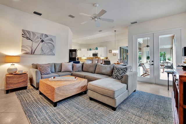 tiled living room with french doors and ceiling fan with notable chandelier