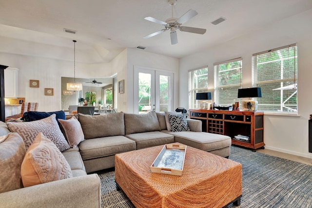 living room with french doors and ceiling fan with notable chandelier