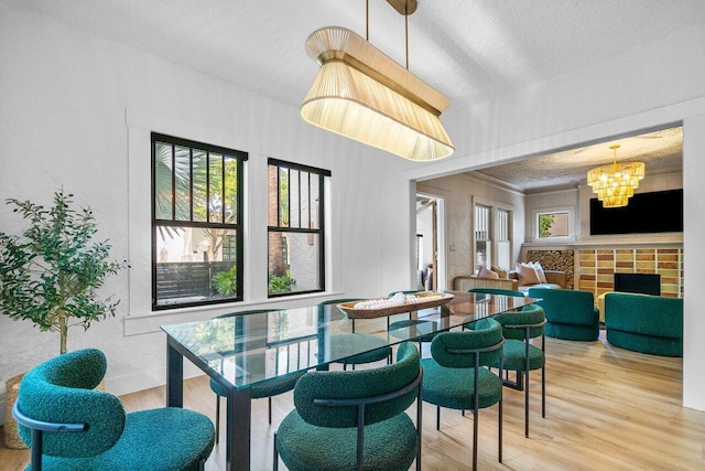 dining area featuring a fireplace, an inviting chandelier, hardwood / wood-style floors, and a textured ceiling