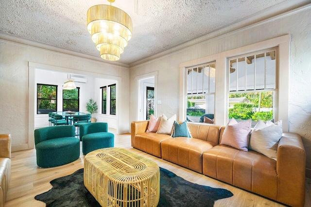 living room with light hardwood / wood-style floors, ornamental molding, a wall unit AC, a textured ceiling, and a chandelier