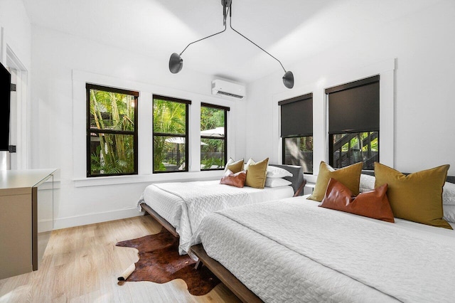 bedroom with an AC wall unit and light hardwood / wood-style floors