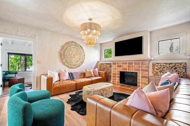 living room with a fireplace, light hardwood / wood-style floors, a textured ceiling, and a chandelier