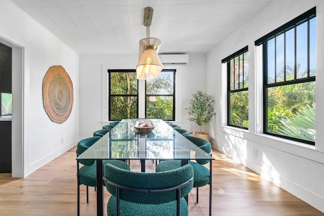 dining space with an AC wall unit, light wood-type flooring, and plenty of natural light