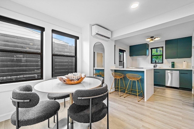 dining area featuring light wood-type flooring, sink, and a wall mounted AC