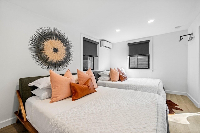 bedroom with a wall unit AC and hardwood / wood-style floors