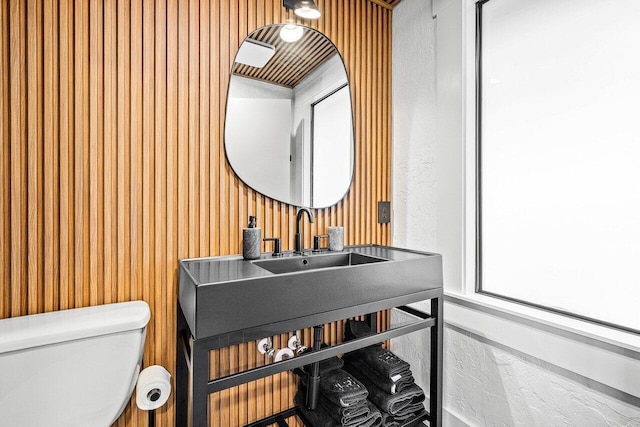 bathroom featuring wooden walls and toilet