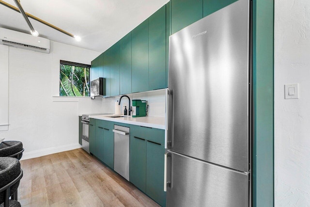 kitchen with light wood-type flooring, stainless steel refrigerator, green cabinetry, sink, and a wall unit AC