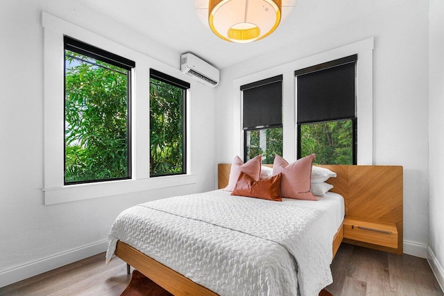 bedroom featuring hardwood / wood-style floors and an AC wall unit