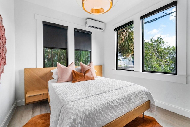 bedroom with an AC wall unit, multiple windows, and hardwood / wood-style flooring