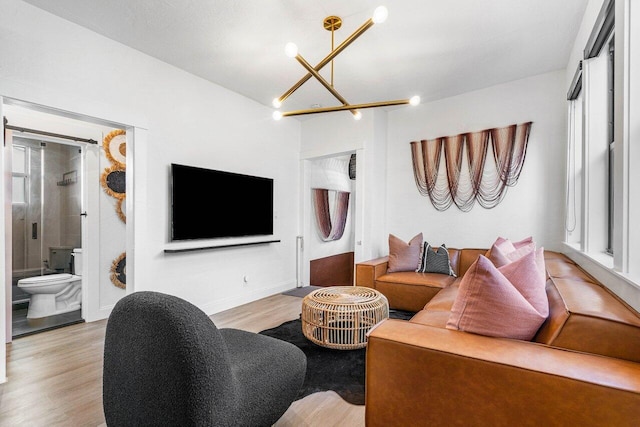 living room with light hardwood / wood-style flooring, a notable chandelier, and a healthy amount of sunlight