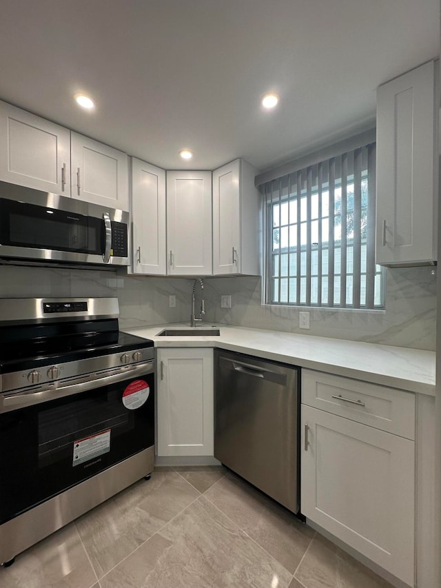 kitchen with stainless steel appliances, white cabinetry, and sink