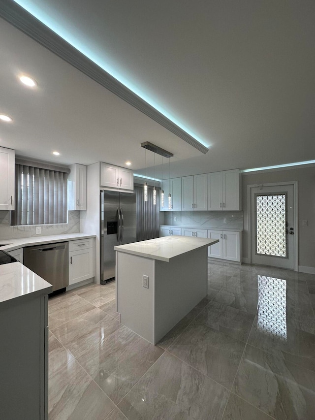 kitchen featuring white cabinets, appliances with stainless steel finishes, decorative light fixtures, and a center island