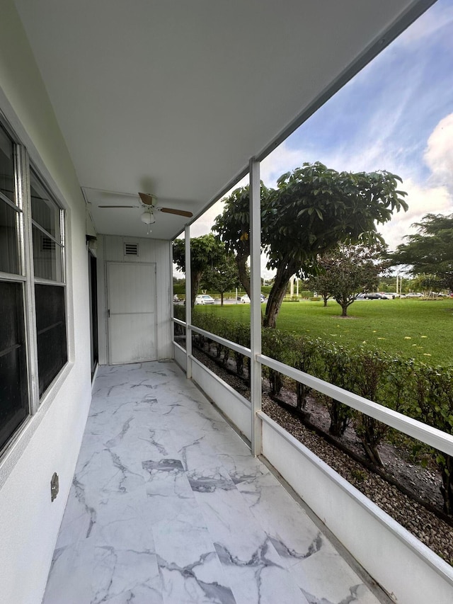 unfurnished sunroom featuring ceiling fan