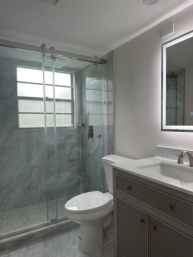 bathroom with toilet, vanity, and a shower with door