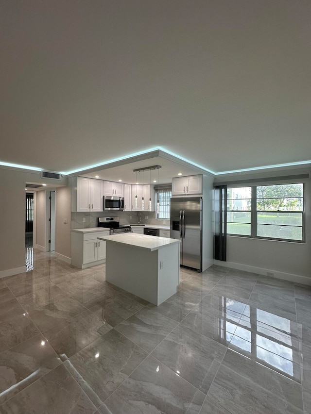 kitchen featuring tasteful backsplash, a kitchen island, white cabinetry, appliances with stainless steel finishes, and pendant lighting