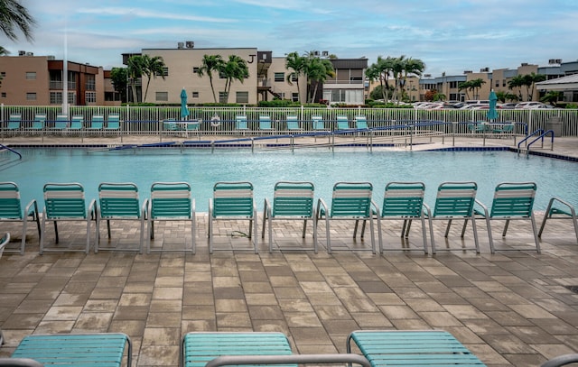 community pool featuring fence, a residential view, and a patio area