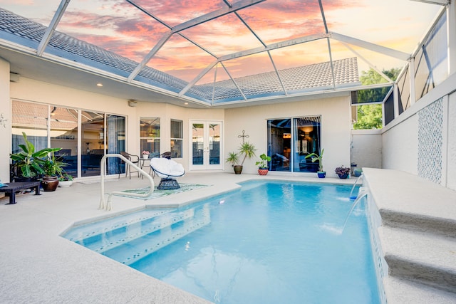 pool at dusk with a lanai, french doors, a patio, and pool water feature