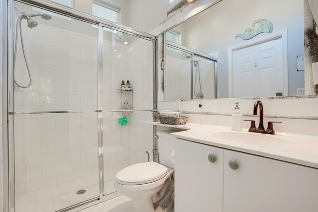 bathroom featuring a shower with door, vanity, and toilet