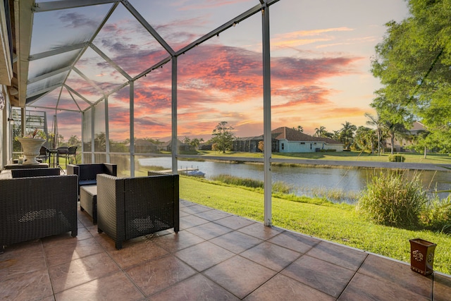 patio terrace at dusk with outdoor lounge area, a water view, glass enclosure, and a yard