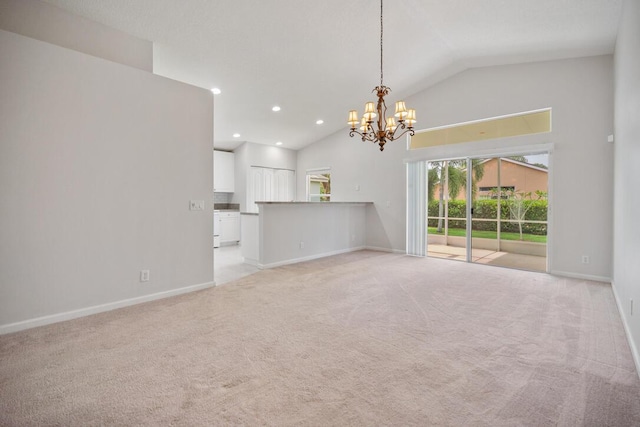 unfurnished living room featuring an inviting chandelier, light carpet, and vaulted ceiling