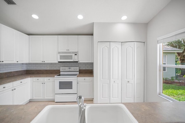 kitchen with decorative backsplash, white cabinetry, and white appliances