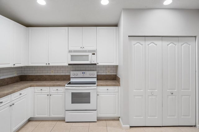 kitchen featuring white cabinets, light tile patterned floors, white appliances, and backsplash