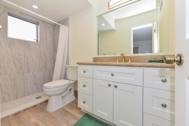 full bathroom featuring toilet, tiled shower, vanity, and wood finished floors